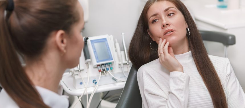 Attractive young woman having toothache, visiting dentist